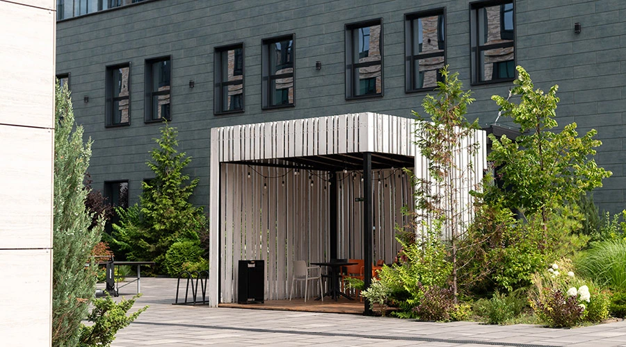 Pergola moderna con schermature laterali inserita in un'area verde aziendale, progettata per creare zone d'ombra e migliorare il comfort degli spazi outdoor.