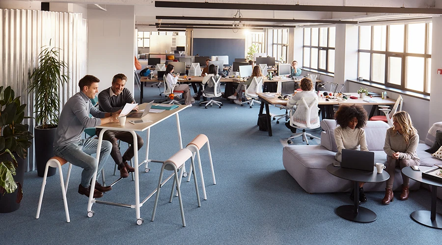 Open space moderno con diverse aree lounge e colleghi negli spazi condivisi