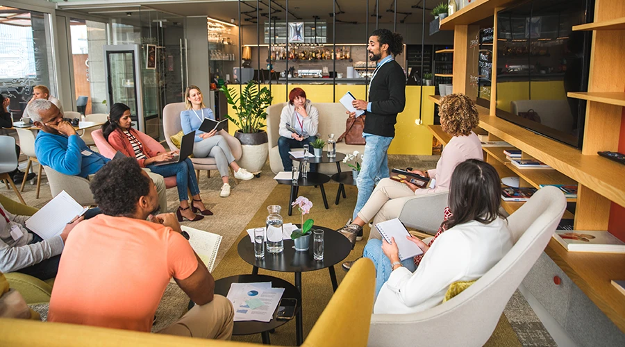 Colleghi in conversazione informale nell’area socializing dell’ufficio