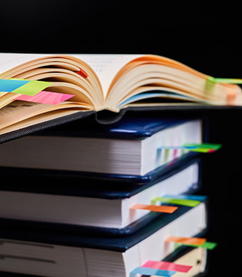 Libri e documenti con Post-it colorati utilizzati per evidenziare e ritrovare rapidamente le informazioni importanti