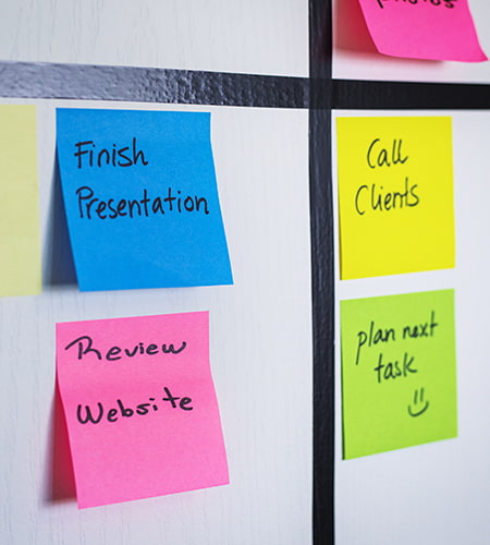 Post-it colorati con attività e promemoria organizzati su una bacheca per la gestione del lavoro
